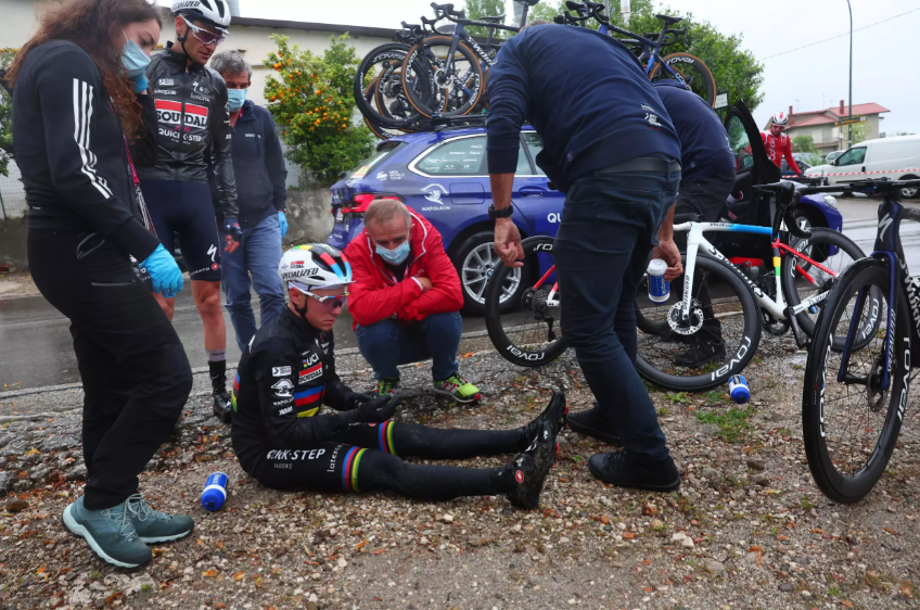 Remco Evenepoel recibe ayuda de miembros de su equipo tras caerse durante la quinta etapa del Giro de Italia, el 10 de mayo de 2023 entre Atripalda y Salerno, al sur del país © Luca Bettini / AFP