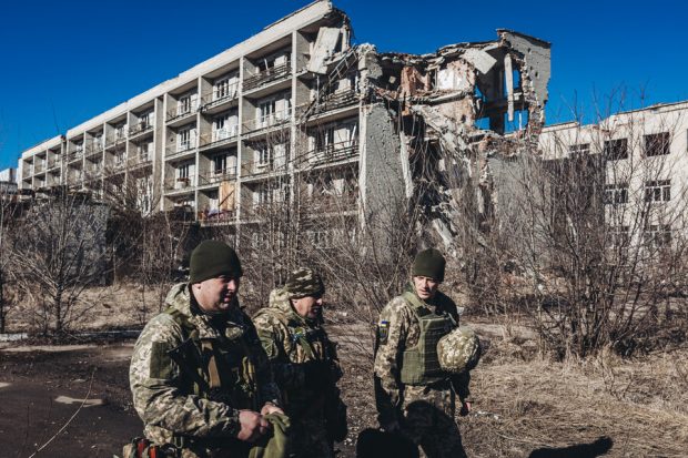 Varios soldados ucranianos caminan frente a un edificio derruido en un pueblo cercano a la línea de contacto, a 15 de febrero de 2022, en Marinka, Oblast de Donetsk (Ucrania). Casi 8 años después del comienzo de la guerra del Donbass (2014), en el este de Ucrania, una posible invasión rusa amenaza de nuevo la tranquilidad del país. 