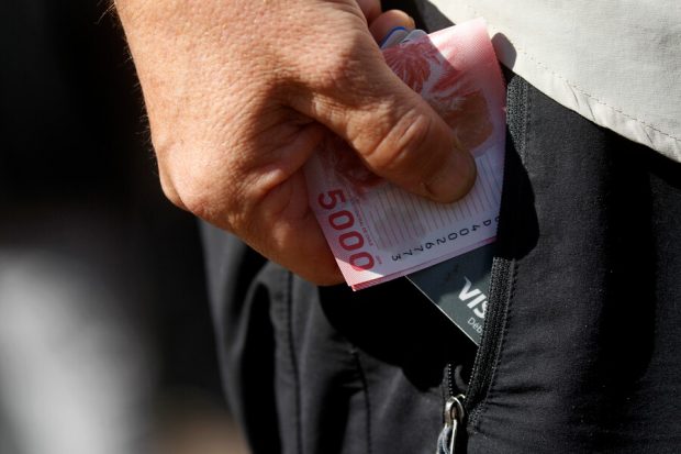 Mano sacando dinero del bolsillo.