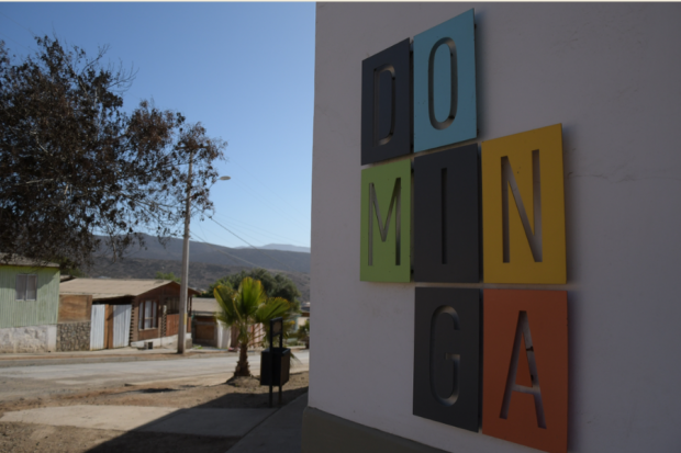 En la imagen se puede apreciar uan ciudad nortina de fondo, a la derecha vemos un letrero en el que se puede apreciar el logo de la minera dominga