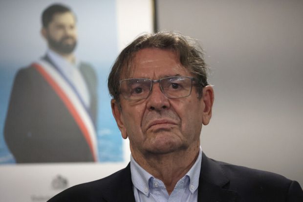 Jaime Gazmuri en primer plano y atrás la imagen oficial del Presidente de la República, Gabriel Boric