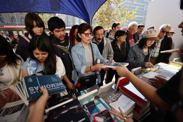 Un grupo de más de 10 personas frente a un stand de libros.