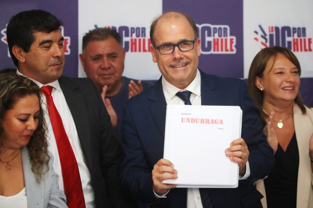 Alberto Undurraga sostiene documento de su candidatura presidencial rodeado de militantes de su partido.