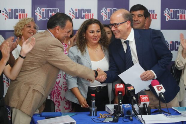 Alberto Undurraga y militante de la DC se dan apretón de mano rodeados de otros militantes del partido.