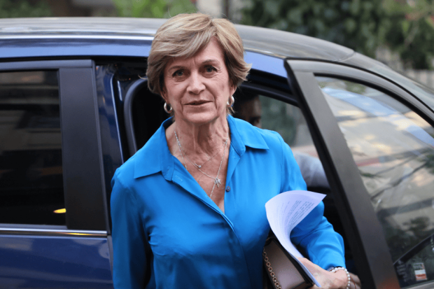 Evelyn Matthei, vestida con una blusa azul, sale de un auto con papeles bajo el brazo