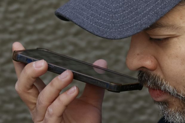 Primer plano de hombre hablando por teléfono por altavoz.