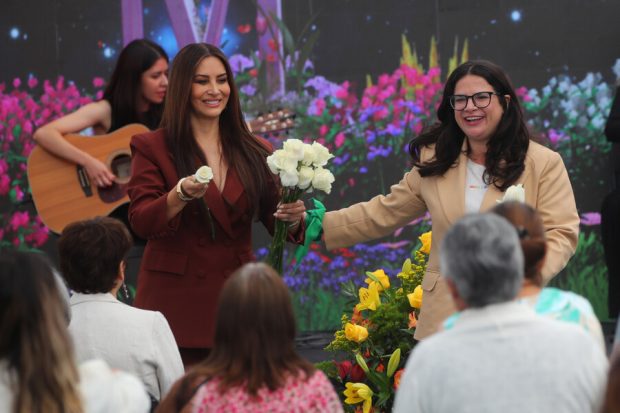 Ministra Orellana y Myriam Hernández, la ultima sostiene un ramo de rosas blancas.