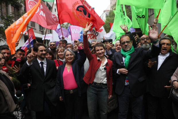 Los candidatos presidenciales del oficialismo (de izquierda a derecha): Gonzalo Winter (FA), Jeannette Jara (PC), Carolina Tohá (PPD) y Jaime Mulet (FRVS). Detrás de ellos una multitud de personas con banderines de distintos colores.