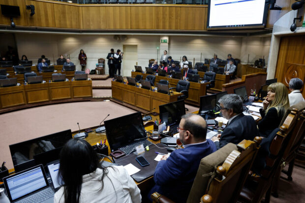 Parlamentarios sentados frente a los computadores de sus puestos en el senado mientras escuchan la alocución del ministro de Hacienda.