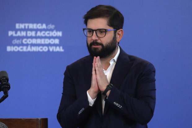 Presidente Gabriel Boric sonrie mientras esta delante de un podio. 