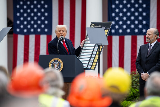 Trump desde un podio sostiene un cartor con los nombres de distintos países y detalles de aranceles. Detrás de él dos banderas de Estados Unidos.