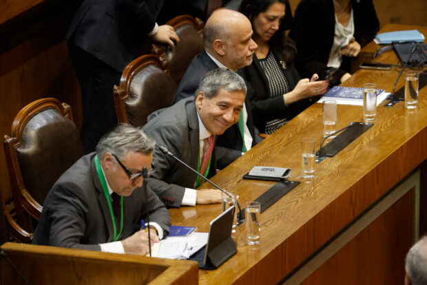 Tres hombres (Cox, Duran y Elizalde) sentados en sitiales mirando a un público que no se ve. A su lado dos mujeres, Aisen Etcheverry y Macarena Lobos) revisando unos documentos. Un mesa de madera brillosa esa frente a ellos.