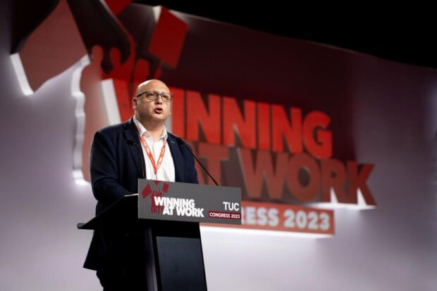 Eric Campos da un discurso detrás de un podio que dice "Winning at work - Congress 2023".