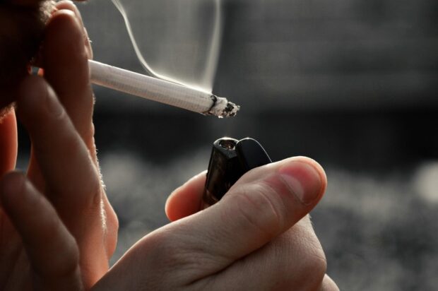 Persona fumando cigarro al aire libre.