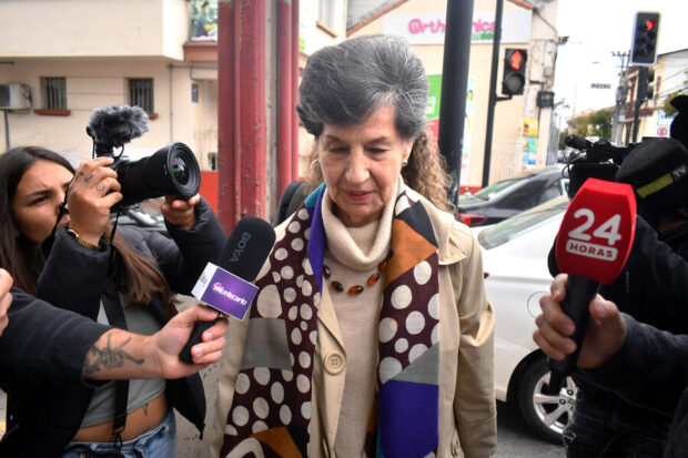 Isabel Allende mirando hacia el piso y rodeada de periodistas y camarógrafas.
