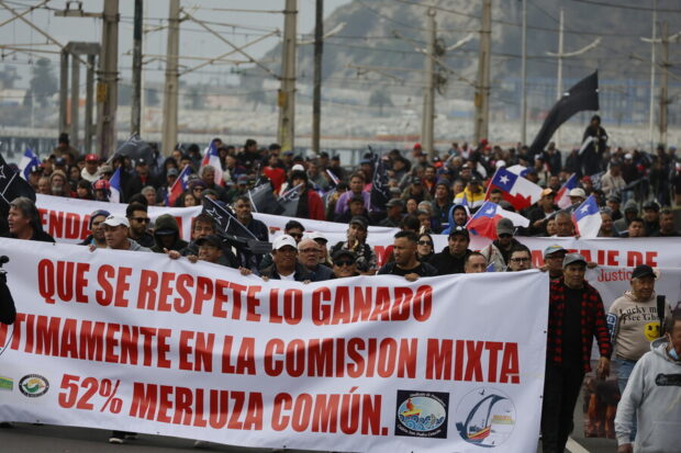 Grupo de manifestantes. Entre la multitud se ven banderas de Chile. Quienes lideran las movilización sostienen un lienzo que dice: "Que se respete lo ganado legítimamente en la comisión mixta, 52% merluza común".
