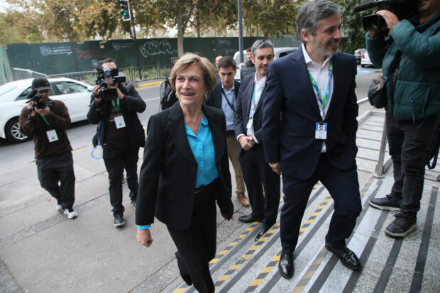 Evelyn Matthei subiendo unas escaleras, alrededor de ella algunos fotógrafos y personal de seguridad.