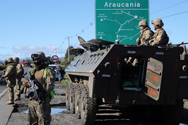 Militares y tanqueta militar, detrás se ve un cartel de transito verde que dice Araucania y muestra un mapa de la localidad.