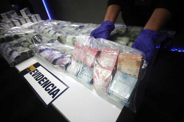 Bolsas de dinero frente a un cartel que dice "Evidencia".