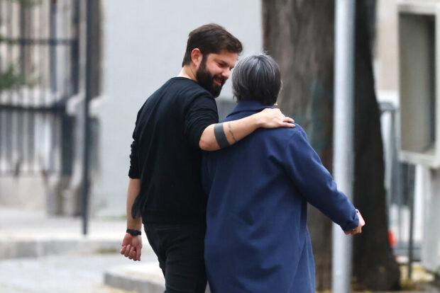 Boric y Jara se ven caminando de espaldas mientras Boric deja su brazo en el hombre de ella.