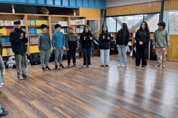Grupo de niños de pie en un salón, en el marco de las actividades de los campamentos musicales de la FOJI en Aysen