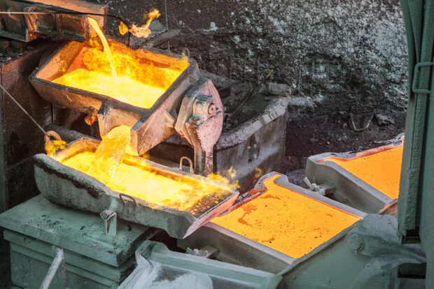 Cobre fundido en estado líquido y brillante, siendo vertido cuidadosamente en moldes de lingotes dentro de una fundición metalúrgica.