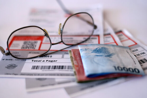 Lentes ópticos y billetes de pesos chilenos sobre cuentas de la luz.