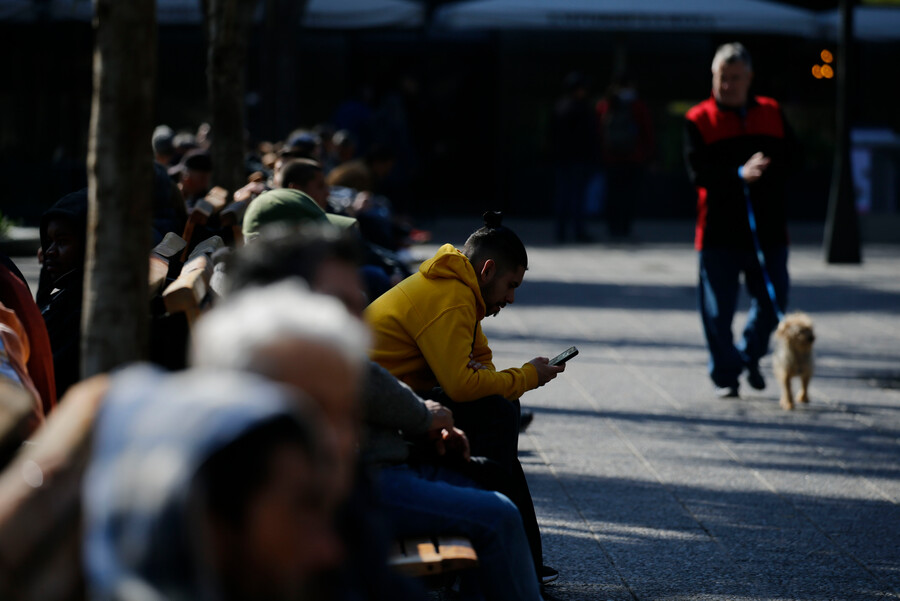 ¿Recesión técnica o estancamiento? Pese a caída consecutiva del PIB, economistas rechazan escenario catastrófico Hilera de personas en una banca, una de ellas es un hombre joven que sobre sale de la banca mientras mira su celular.
