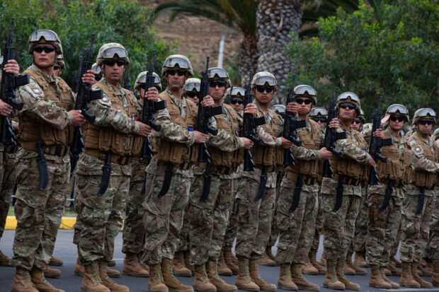 Grupo de soldados en formación, vestidos con uniforme de camuflaje y portando fusiles.