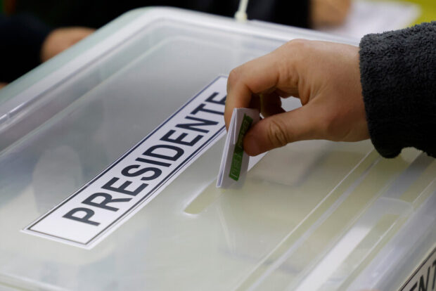 Mano introduce voto en urna que dice "Presidente".
