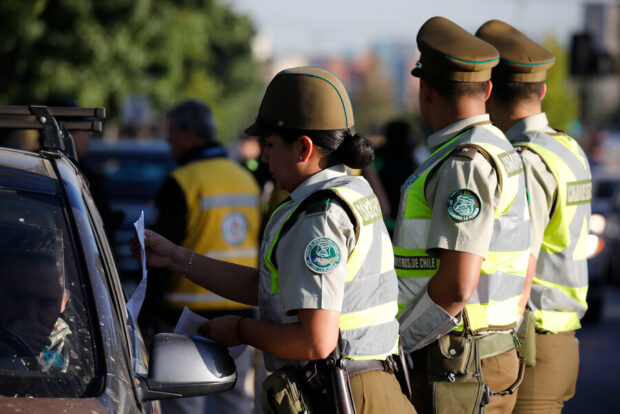 Carabineros realizando un control vehicular a un auto.