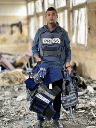 El foto periodista Hossam Shabat sosteniendo los equipamientos de sus colegas aseinados, poco tiempo el también falleció