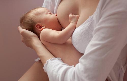 Bebe recién nacido toma leche del pecho de su madre.