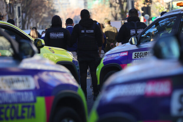 Autos de seguridad ciudadana alineados uno al lado de otro y funcionarios de seguridad vestidos de negro se ven de espaldas.