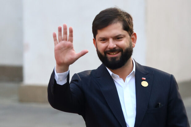 Presidente Gabriel Boric saludando con la mano y sonriendo.