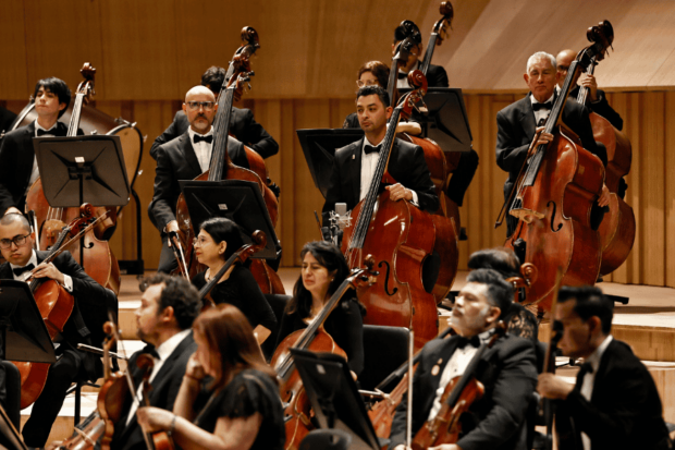 Sección de cuerdas de la Orquesta Sinfónica Nacional sobre el escenario de la Gran Sala Sinfónica Nacional de la U. de Chile