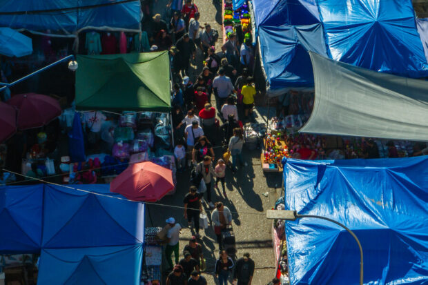 Vista aérea de los toldos azules de Meiggs. Se ven a personas comprando y caminando entre los toldos. 