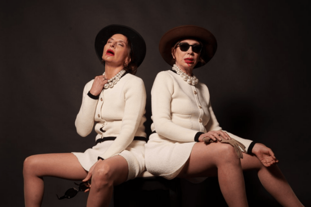 Antonia Zegers y Patricia Rivadeneira calzando trajes blancos y sombreros, con lentes de sol y zapatos negros, en una de las escenas de la obra "Una mujer llena de vicios"