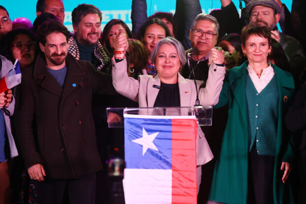 Winter, Jara y Tohá alzan sus manos unidas para mostrar unidad. Atrás de ellos militantes del oficialismo.