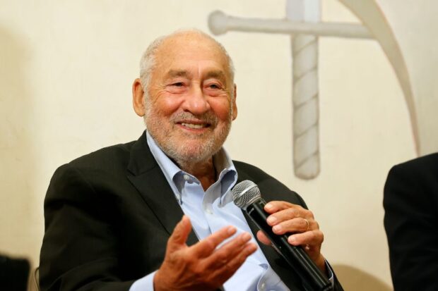 El Premio Nobel de Economía, Joseph Stiglitz, habla con un micrófono en la mano mientras sonríe.