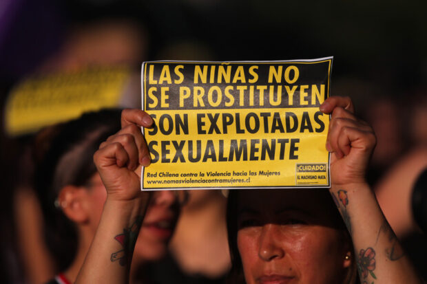 Mujer sostiene un cartel amarillo en una manifestación que dice: "Las niñas no se prostituyen, son explotadas sexualmente".