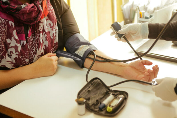 Un profesional de la salud mide la presión arterial a un paciente. Brazalete de presión arterial en el brazo de una persona. Equipo médico para control de diabetes y presión.