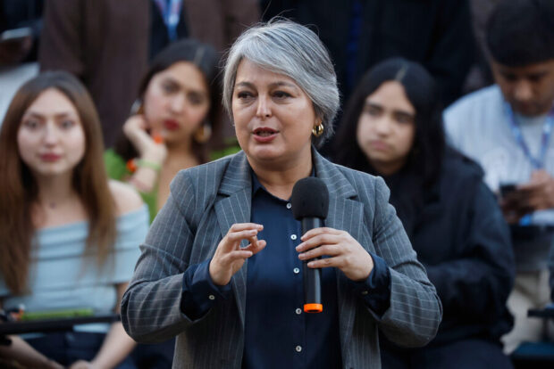 Candidata presidencial del pacto Unidad por Chile, Jeannette Jara, habla con un micrófono en la, detrás de ella se ven jóvenes universitarios sentados escuchándola.