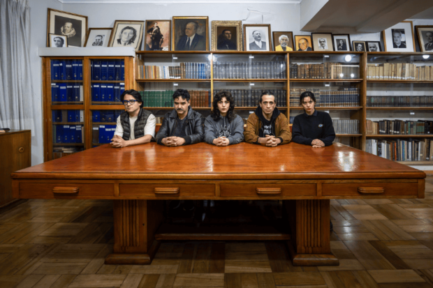 Elenco de la obra "La Fundación" sentados en una mesa de escritorio amplia.