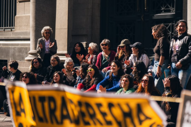 Personas en protesta feminista sostienen un cartel amarillo que dice “La ultraderecha quita derechos. ¡Que no te engañen!” en el centro de Santiago.