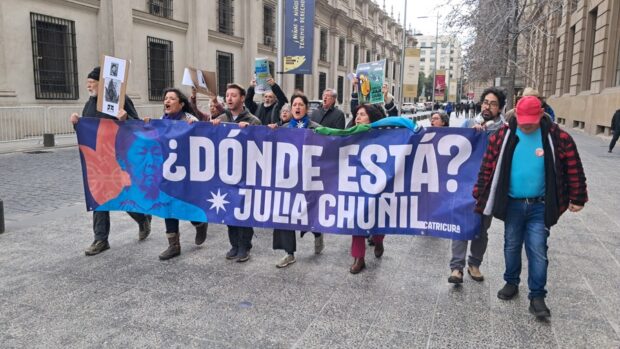 Personas sostienen un cartel morado y con letras blancas que dice "¿Dónde está Julia Chuñil?".