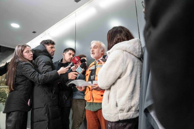 Presidente ejecutivo de Codelco, Rubén Alvarado, vestido con chaleco naranja y rodeados de periodistas de distintos medios de comunicación.