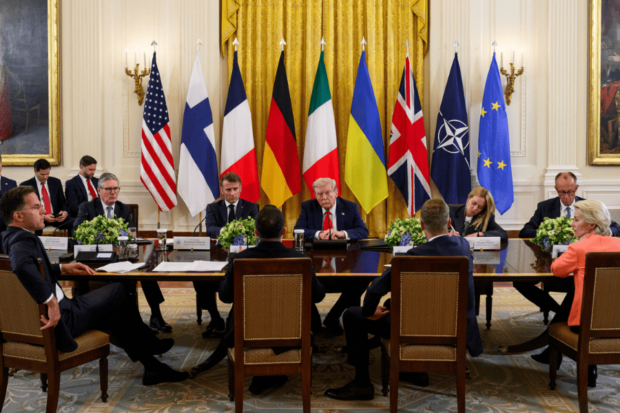 Autoridades europeas y Trump se ven sentados en una mesa larga, detrás de ellos las banderas de los distintos países.