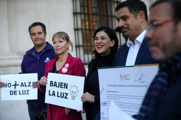 Grupo de parlamentarios chilenos sostienen carteles con mensajes contra el alza de la luz, frente a La Moneda.