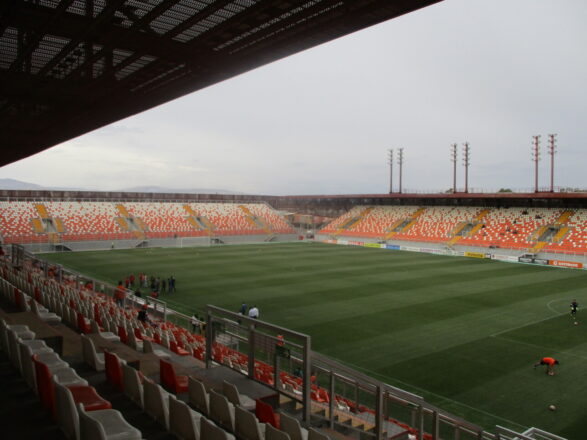Vista interior del Estadio Municipal de Calama con gradas vacías y campo de césped.